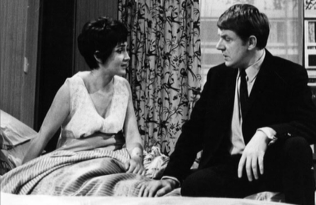 Husband sits on bed talking to his wife