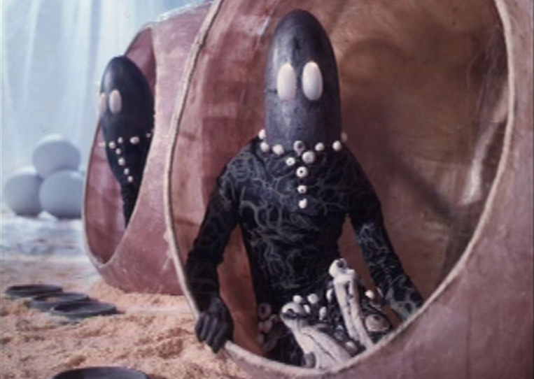 large eyed alien sitting in pod