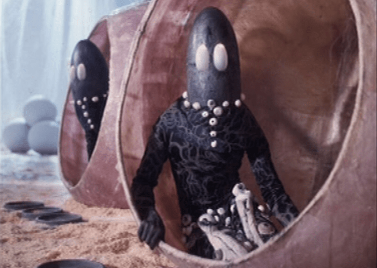 large eyed alien sitting in pod